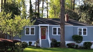 A single-story house with a red front door, white trim, and a small front porch.