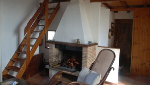 A cozy living room with a fireplace, wooden staircase, and a comfortable chair. - Apartment in Farmhouse for Families with Pool (Porchiano del Monte - Amelia)