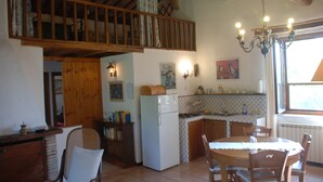 A kitchen with wooden beams, a dining table, chairs, a refrigerator, and a window with curtains. - Apartment in Farmhouse for Families with Pool (Porchiano del Monte - Amelia)