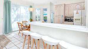 A modern kitchen with a central island, bar stools, wooden cabinets, and a view of the outdoors. - Palm Harbor Paradise | Spacious Home with Pool & Hot Tub (Palm Harbor)