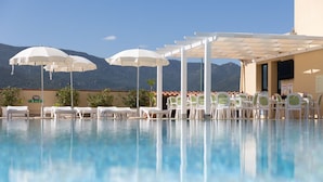 A pool with white umbrellas and chairs, a pergola, and mountains in the background. - One bedroom apartment premium (4 people) - Residence Le Fontane (Villasimius)