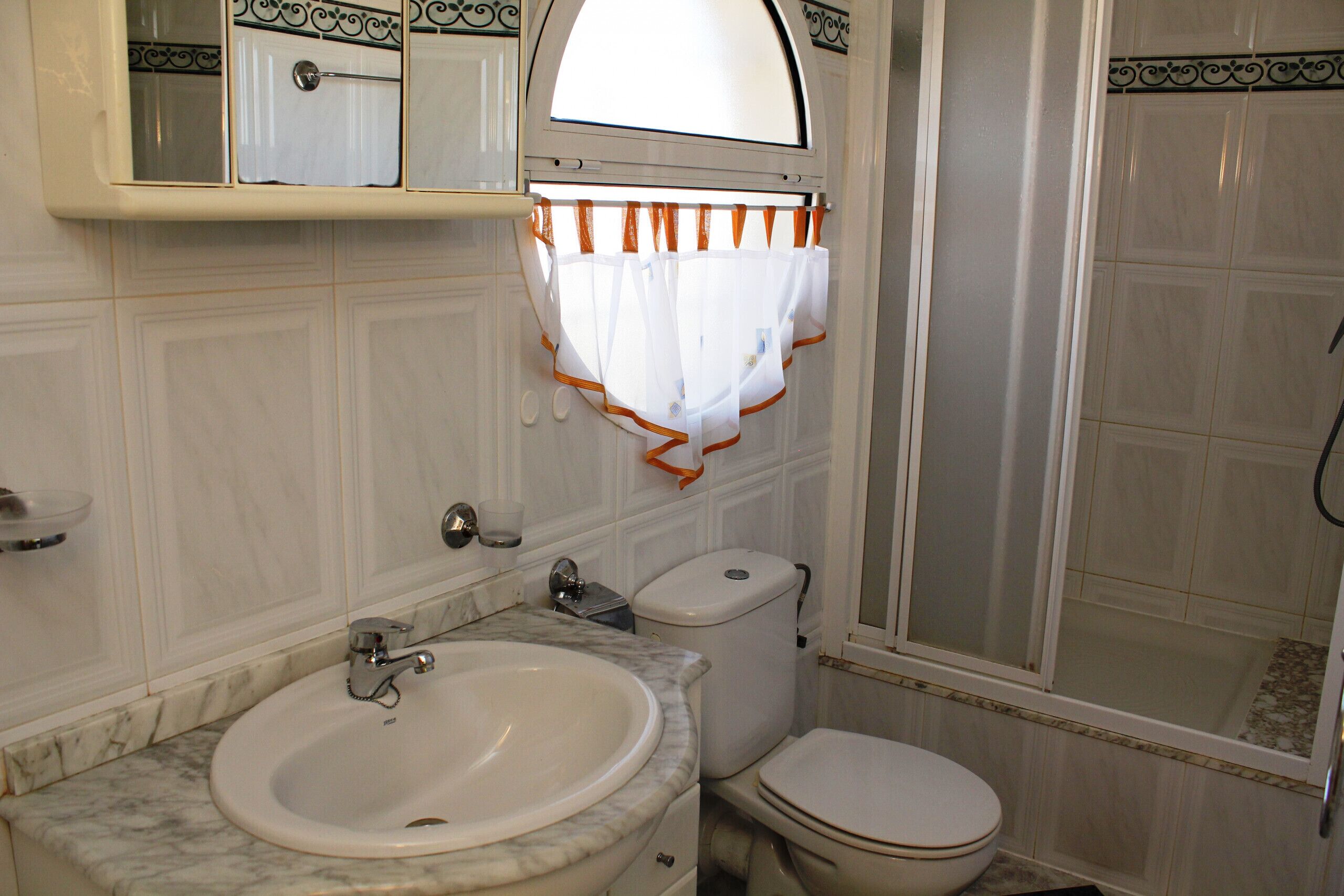 A bathroom with a marble sink, a toilet, and a shower with a glass door.