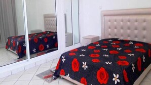 Un dormitorio con cama, mesita de noche y espejo.