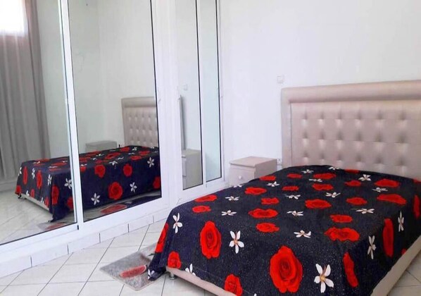 A bedroom with a bed, a nightstand, and a mirror.