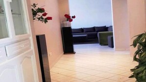 Un pasillo con piso de baldosas que conduce a una sala de estar con un sofá y una planta.