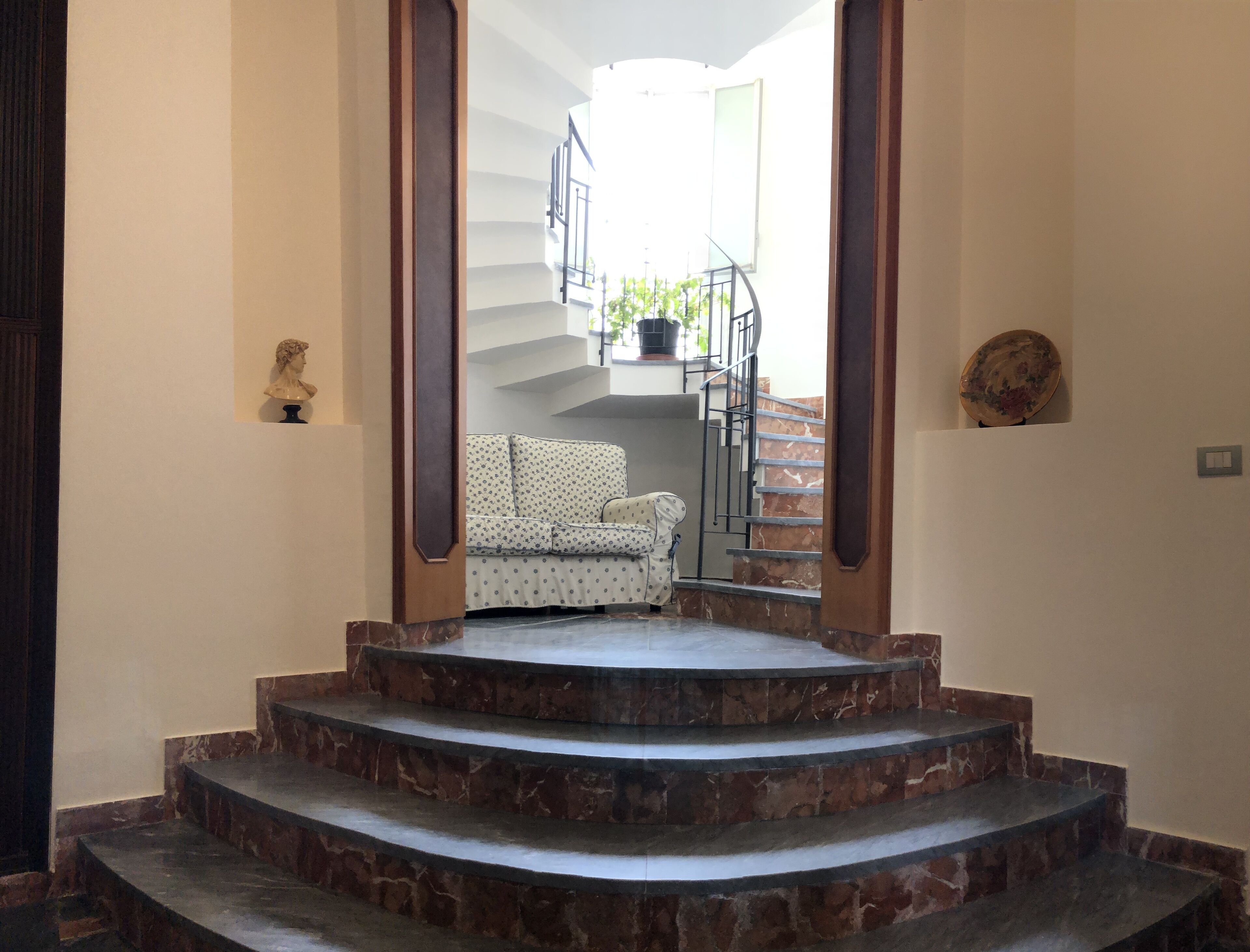 A staircase leading to a balcony with a patterned sofa and a potted plant.