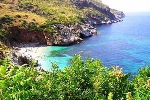 A coastal landscape with a rocky shoreline and clear blue waters.