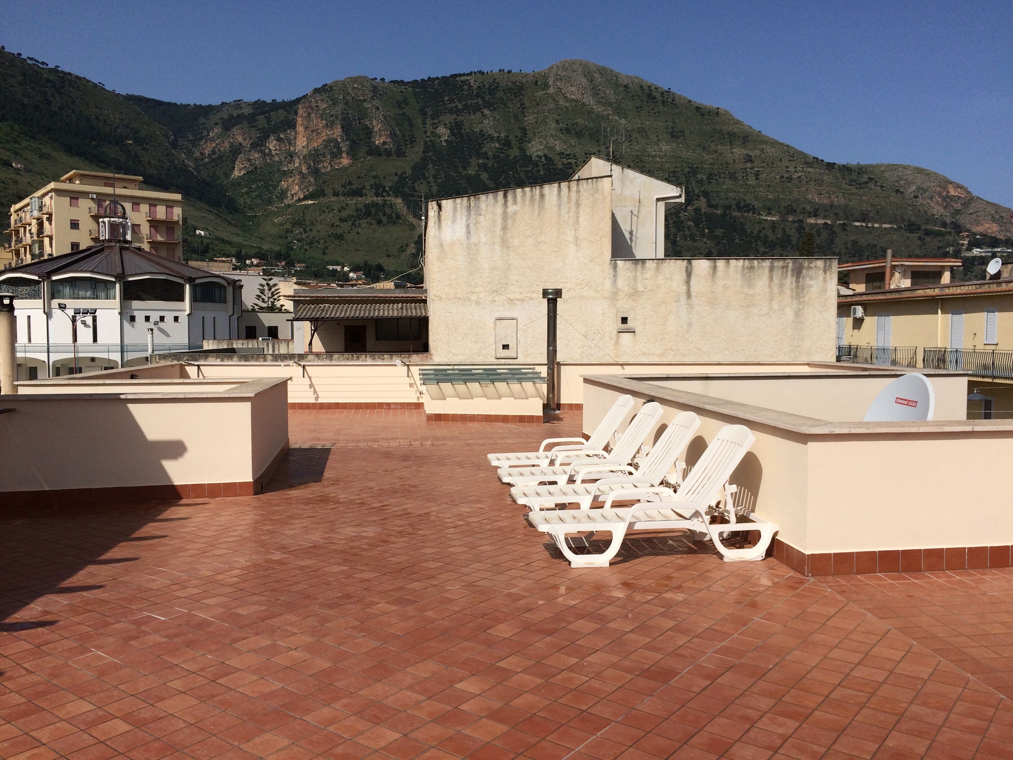 Una terraza en la azotea con tumbonas blancas, una mesa de billar y vistas a una montaña.