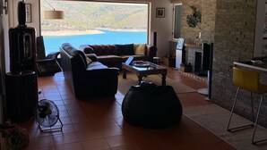 A spacious living room with a large window overlooking a scenic view, wooden ceiling, and modern furnishings. - House in Castelo de Bode, blue lake (Castelo de Bode)