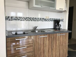 Eine Küche mit Spüle aus Edelstahl, Holzschränken und einer gefliesten Spritzschutzwand.