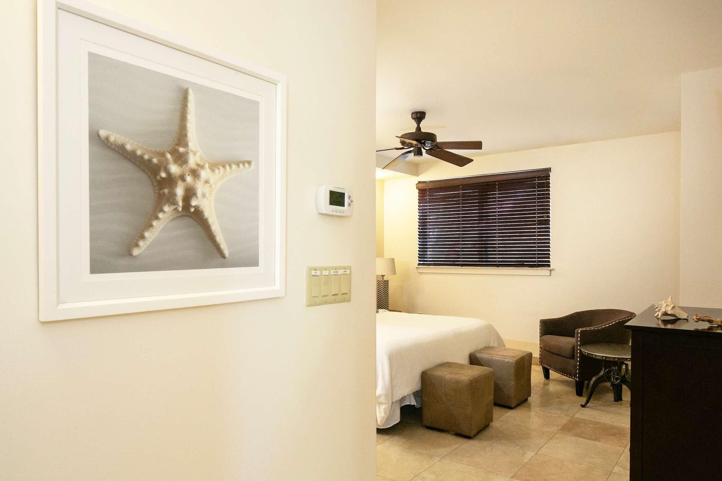 A bedroom with a bed, a ceiling fan, a window with blinds, a chair, and a desk.
