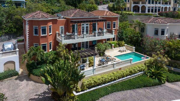 A multi-story hotel with a swimming pool, outdoor seating, and lush landscaping.