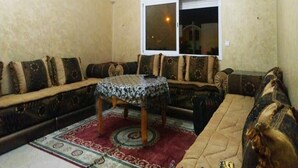 Una sala de estar con un sofá, una mesa redonda y un tapete estampado.