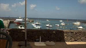 Une vue sur un port avec des bateaux amarrés, un mur de pierre et un parasol.