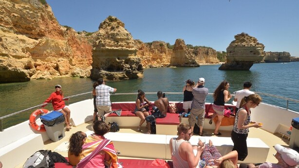 Un barco con pasajeros disfrutando de la vista de acantilados rocosos y aguas tranquilas.