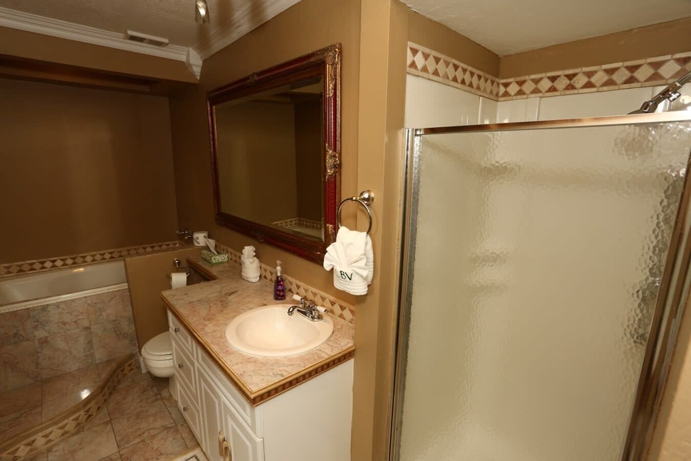 A bathroom with a marble sink, a large mirror, a towel rack, and a glass shower enclosure.