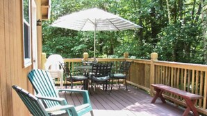Eine Holzterrasse mit Gartenmöbeln, darunter Stühle und ein Tisch.