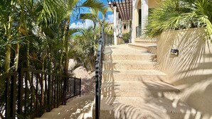 A staircase leading to a building with a pergola and palm trees. - Frangipani Private Pool and Tesla Backup! (St. John)