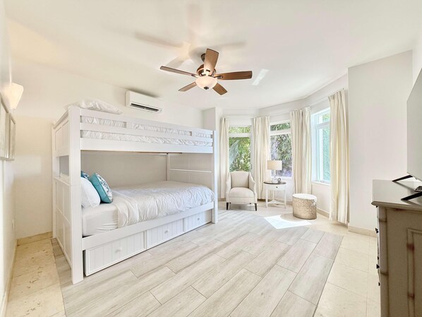 A bedroom with a bunk bed, a ceiling fan, a chair, a small table, and a laptop on a desk. - Frangipani Private Pool and Tesla Backup! (St. John)
