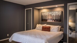 A bedroom with a large bed, a painting above the bed, and a closet with a mirror. - Branson Condo at Pointe Royale with Indoor Pool and Hot Tub on Taneycomo Lake ne (Branson)