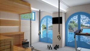 Een sportschool met trainingsapparatuur, een sauna en uitzicht op het zwembad.