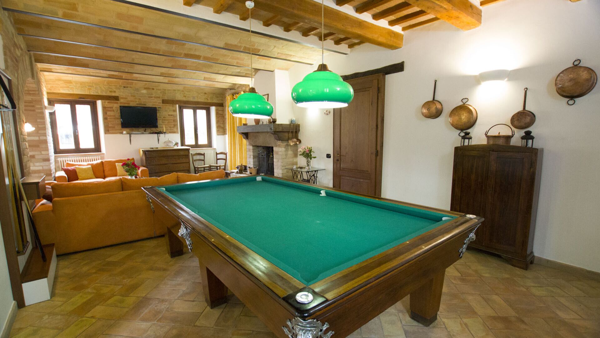 Una sala de estar acogedora con mesa de billar, vigas de madera y chimenea.