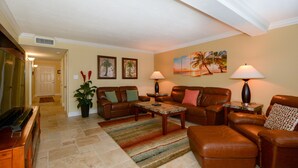 A living room with two leather sofas, a coffee table, a TV, and a potted plant. - Condo with Gulf View just steps to our private Siesta Key Beach! (Sarasota)