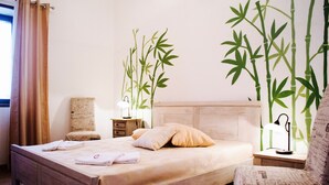 A neatly made bed with pillows, a bedside table with a lamp, and a chair with a wall-mounted plant. - TENUTA LE CRIE, VILLETTA RESIDENCE with swimming pool and tennis court (Muro Leccese)