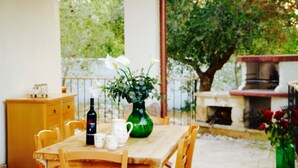 A wooden dining table with chairs, a green vase with flowers, a wine bottle, and a pitcher on the table. - TENUTA LE CRIE, VILLETTA RESIDENCE with swimming pool and tennis court (Muro Leccese)