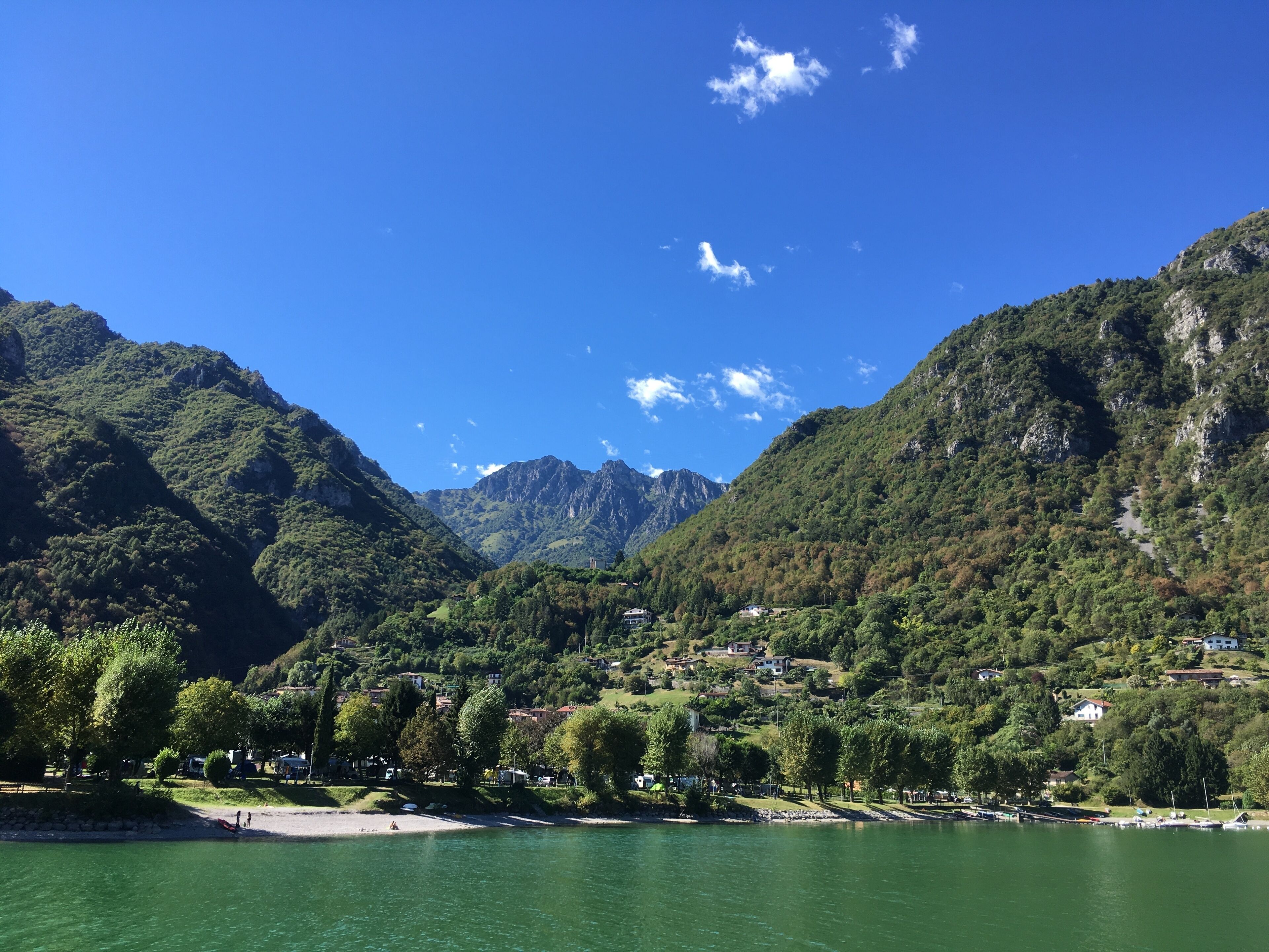 A mountainous landscape with a lake, houses, and trees.