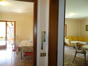 Comedor con mesa para cuatro sillas y vista a un jardín por una puerta abierta.