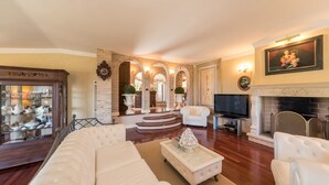 A spacious living room with a large white sofa, a fireplace, and a television. - Fontespina 6, Emma Villas (Conca degli Ulivi)