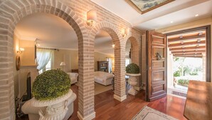 A spacious hallway with brick arches, a white sofa, and a wooden door leading to an outdoor area. - Fontespina 6, Emma Villas (Conca degli Ulivi)