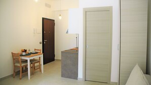 A small, well-lit room with a wooden dining table and chairs, a small cabinet, and a closed door. - The sunny House "In the center"  (Catania)