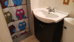 A bathroom with a white sink, dark cabinets, and a shower curtain with owl designs.