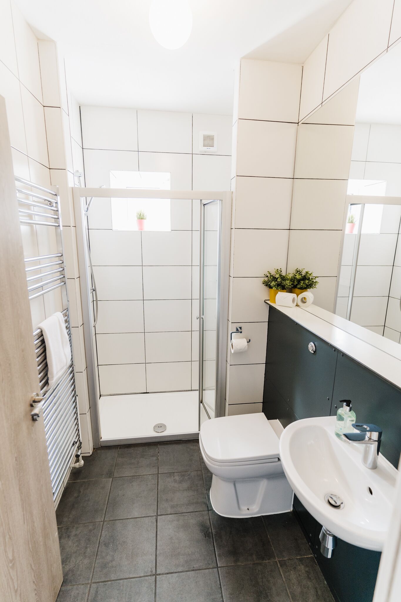 Une salle de bain moderne avec des toilettes blanches, un lavabo et un espace douche.