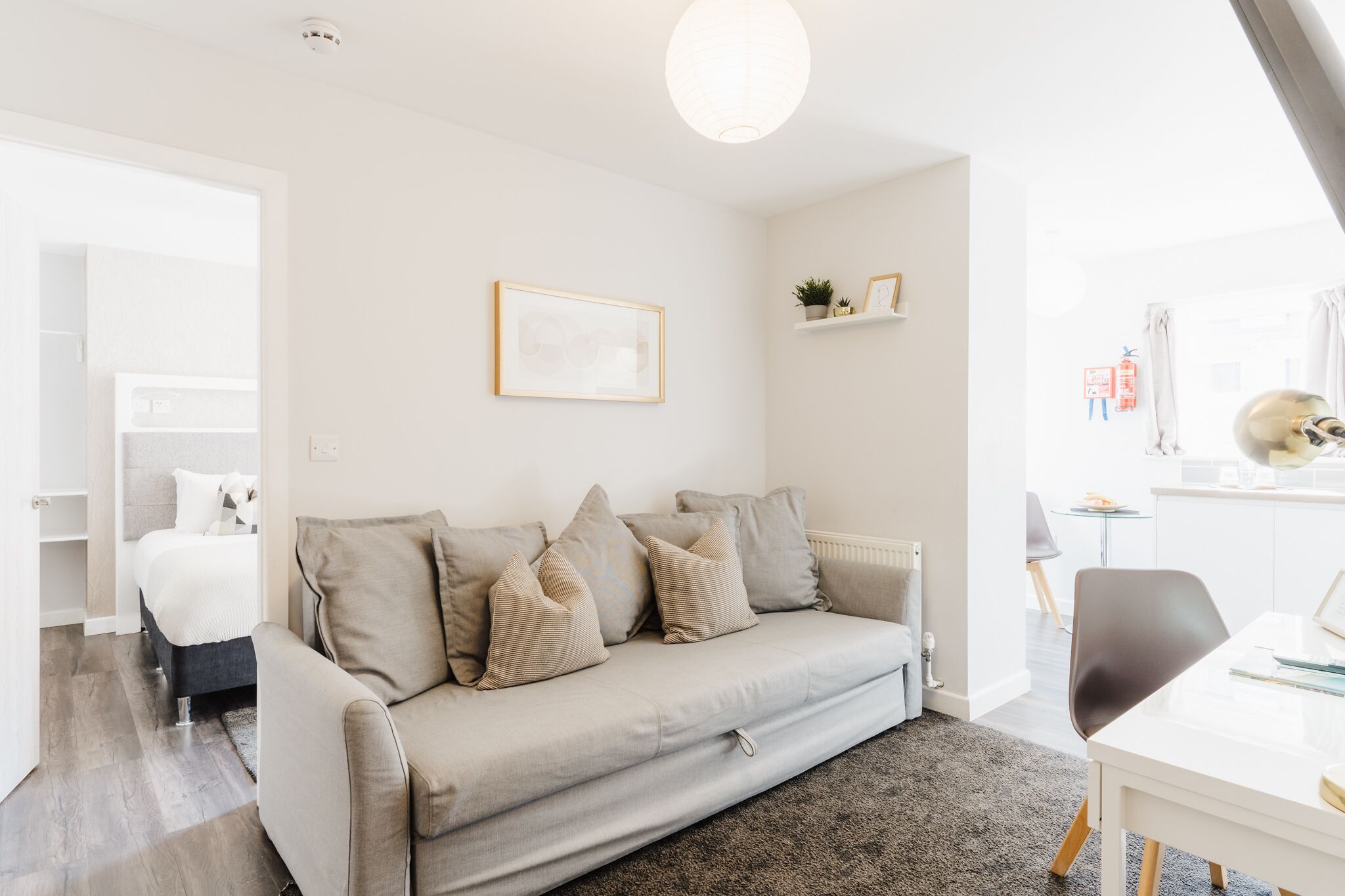 A modern living room with a sofa, a dining table, and a kitchen area in the background.
