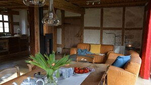 A cozy living room with a sofa, a dining table with a vase of flowers, and a kitchen area in the background. - Lichtblick apartment near Bad Windsheim, fireplace, garden, barbecue, panorama screen, massage (Ickelheim)