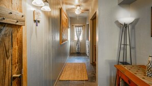 A hallway with wooden walls, a ceiling fan, and a rug leading to a door. - Ranch Home with Guest Suite Located on 2 acres of Orchard (Waddell)
