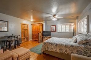 Cozy retreat with a large bed, wardrobe, TV, and ceiling fan, offering a comfortable space to unwind.