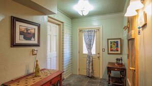 A hallway with a wooden bench, a door with a patterned curtain, and a small table with a decorative item. - Ranch Home with Guest Suite Located on 2 acres of Orchard (Waddell)
