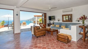 A spacious living area with a large window overlooking a scenic ocean view, furnished with leather sofas and a coffee table. - Private villa- 3 bdrm & 4 bath with ocean views and new private infinity pool  (Puerto Vallarta)