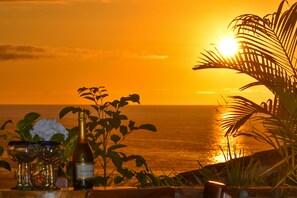 A sunset view with a bottle of champagne and glasses on a table.