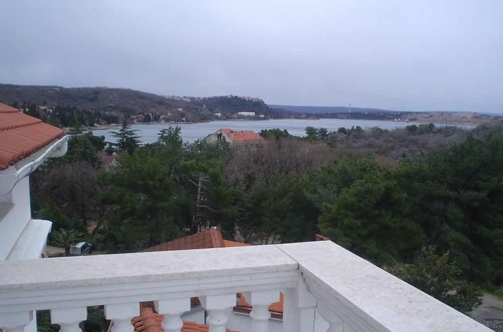 Ein Balkon mit Blick auf einen See und Hügel.