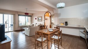 A modern kitchen with a wooden dining table, chairs, and a coffee maker. There is a large window with a view of the outdoors. - Residence Schuler - Apartment 'B' with sea-Etna view  (Taormina)