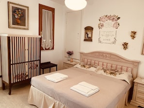 Classic design with a large bed, wooden crib, and decorative touches.