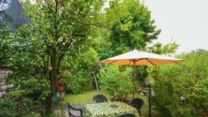 Eine Terrasse mit Tisch und Stühlen, umgeben von üppiger Bepflanzung und einem Baum mit Früchten.