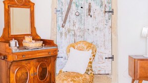 Ein Zimmer mit einem Holzkasten, einem Stuhl und einer Tür mit abgetragener Farbe.