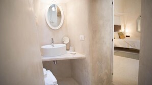 Ein kleines Badezimmer mit rundem Spiegel, Waschbecken und Toilette.