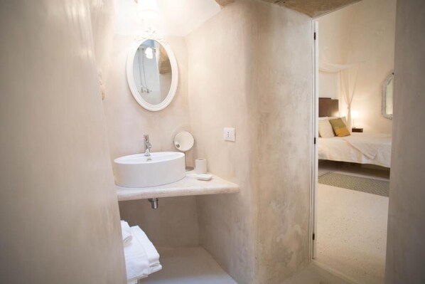 Ein kleines Badezimmer mit rundem Spiegel, Waschbecken und Toilette.